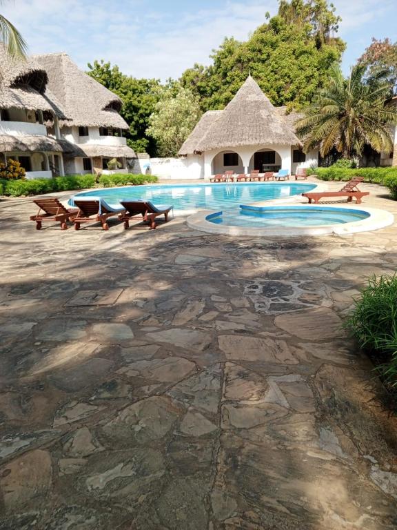 a swimming pool with benches and a resort at Savanna Breeze Villa in Malindi