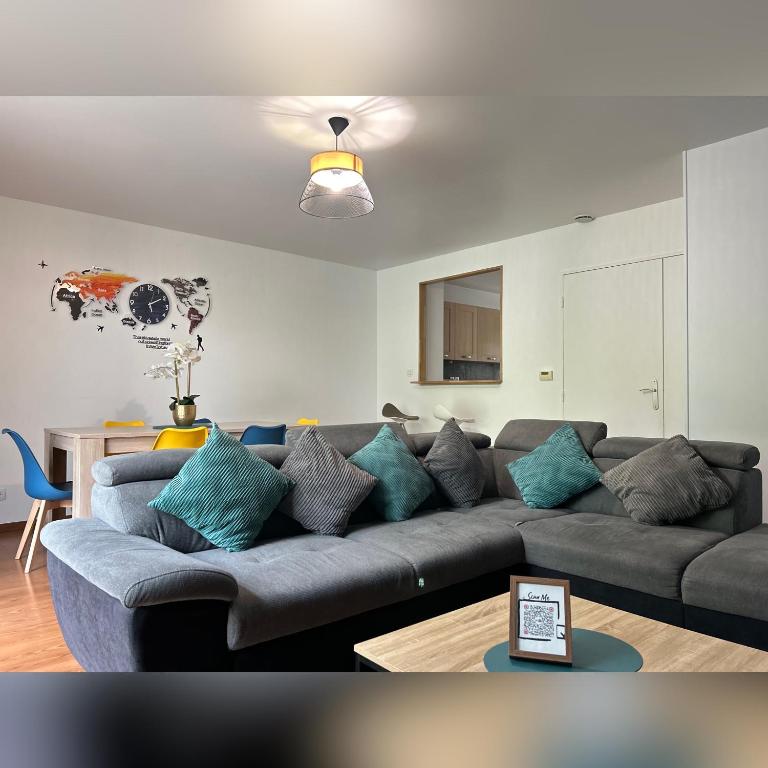 - un salon avec un canapé gris et des oreillers bleus dans l'établissement LE DUPLEX CHESSY - 15min From Disneyland - 2 Private Parkings - Garden - KingSize & QueenSize Bed - SuperMarket behind the house, à Chessy