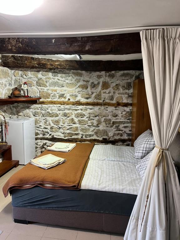 a bedroom with a bed with a brick wall at Cottage Modrich in Struga