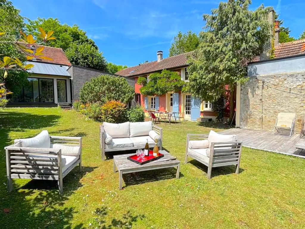 a yard with three chairs and a table and a house at Villa Oscar in Les Mesnuls