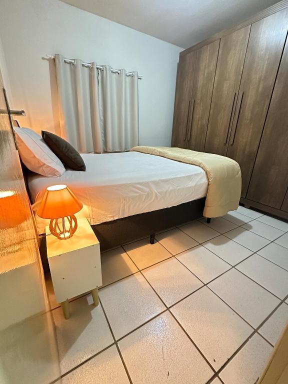 a bedroom with a bed and a lamp on a tiled floor at J Lindo Sobrado 2 quartos em condomínio no Centro in Marília