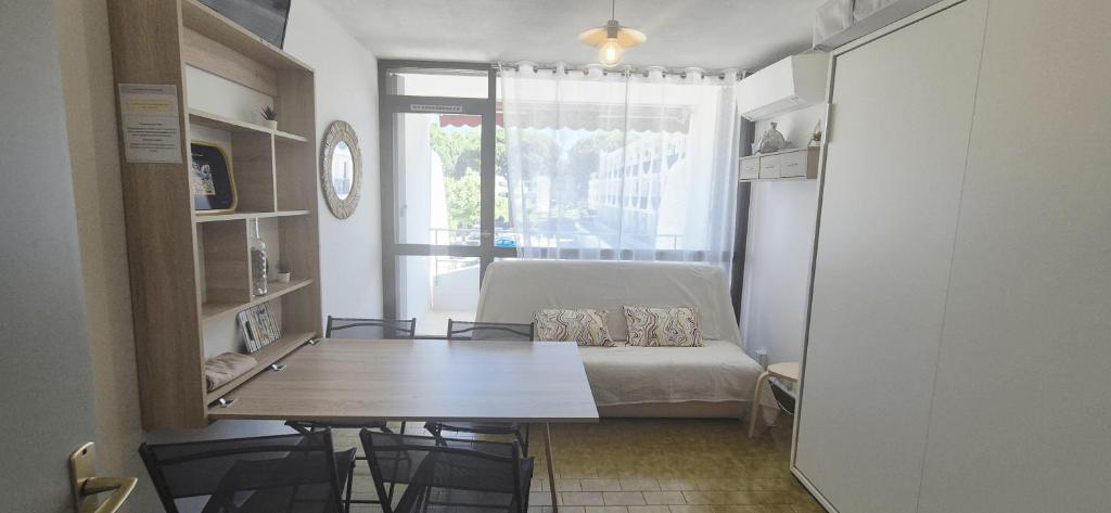 ein Zimmer mit einem Tisch und einem Bett und einem Fenster in der Unterkunft Studio cv, parking, plage 5 mn in La Grande-Motte