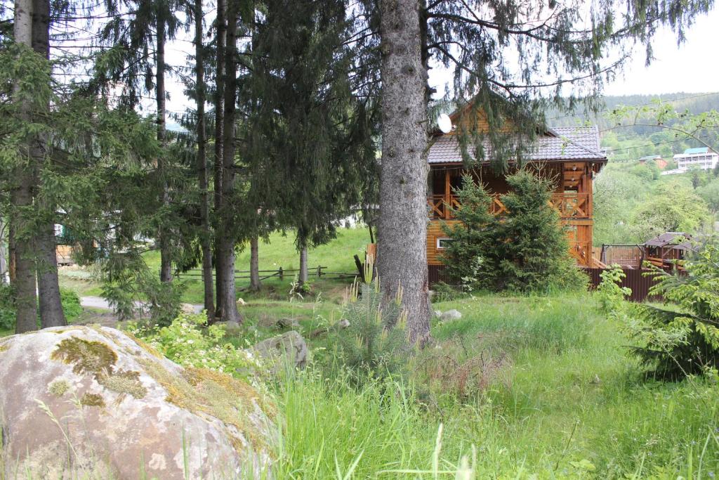 una cabaña de madera en el bosque con una roca y árboles en Krym, en Yaremche