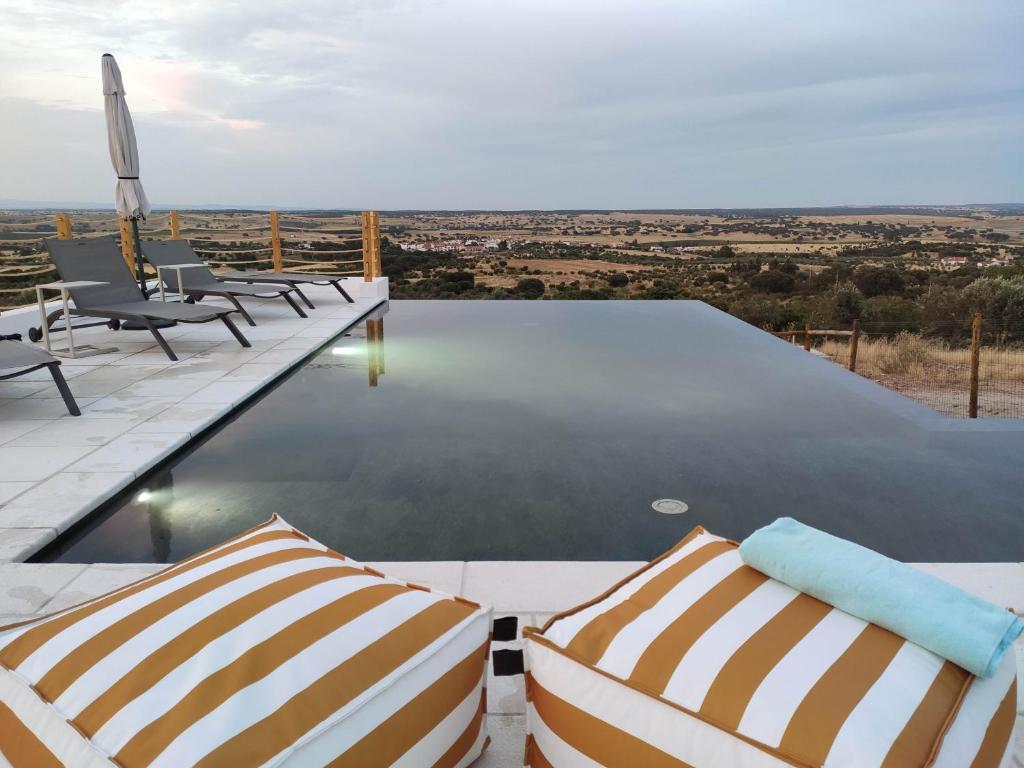 a pool with chairs and a view of the countryside at Monte da Boavista de Cima - Casa de Campo 