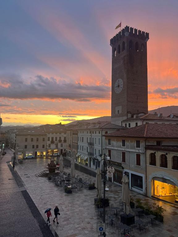 a building with a clock tower with a sunset in the background at Ca' Garibaldi Rooms in Bassano del Grappa