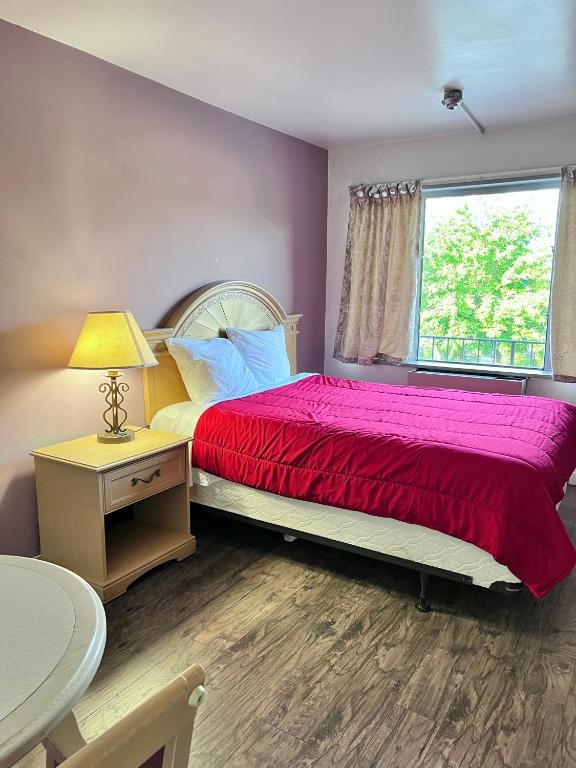 a bedroom with a bed with a red blanket and a window at 6267 Persepolis Inn in Niagara Falls