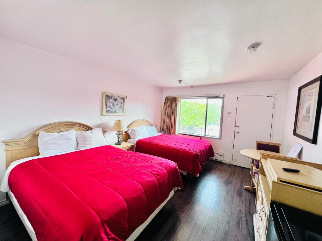 two beds in a room with red sheets at 6267 Persepolis Inn in Niagara Falls