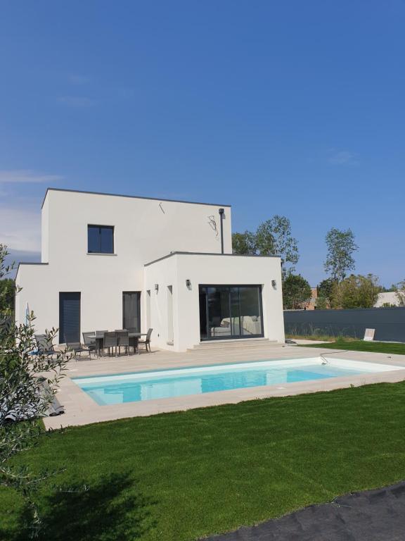 une maison blanche avec une piscine dans la cour dans l'établissement La villa Dorée, à Sérignan