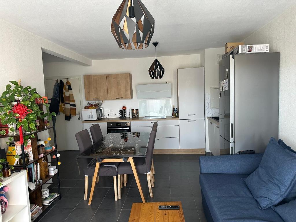 une cuisine et une salle à manger avec une table et un canapé bleu dans l'établissement résidence proche de la mer, à Port-de-Bouc