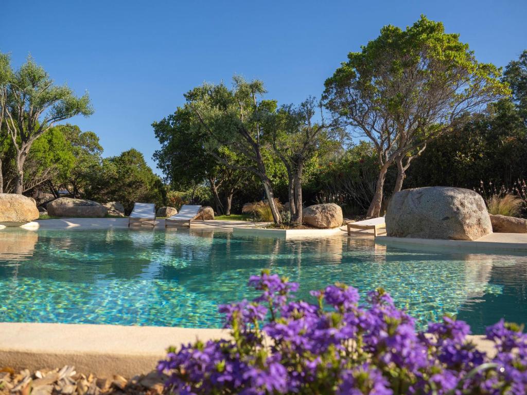 une piscine avec des arbres et des fleurs violettes dans l'établissement Villa Mamma, à Zonza