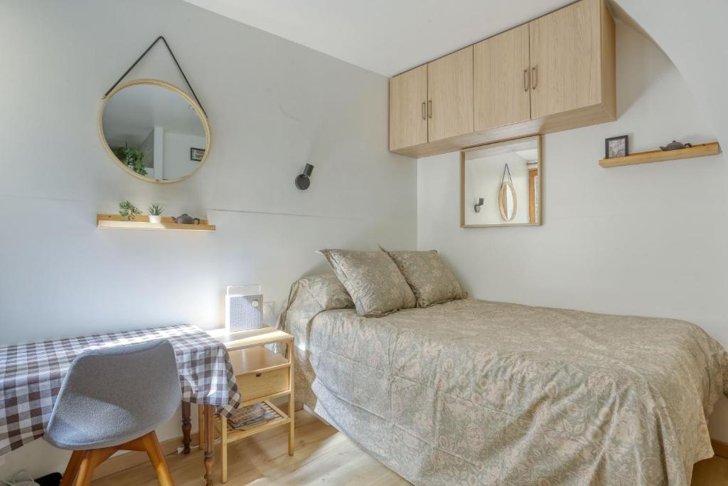 une chambre avec un lit, une chaise et un miroir dans l'établissement Le Lully - Versailles, à Versailles