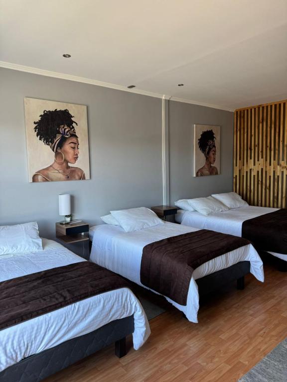 a hotel room with two beds and paintings on the wall at Hotel y Restaurant Mackenna in Osorno