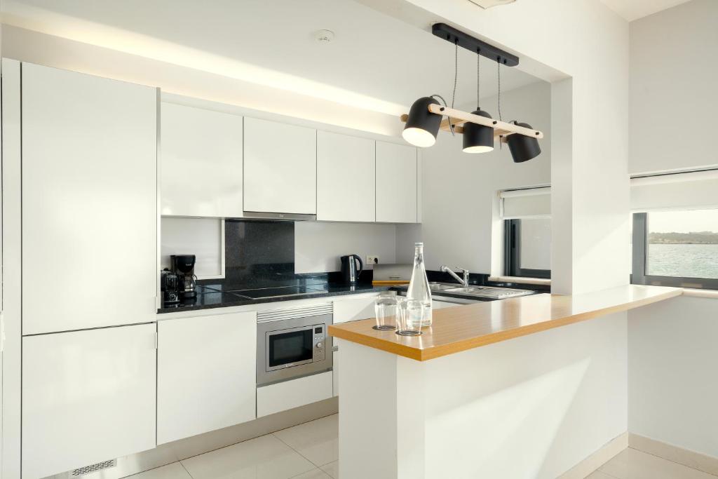 a white kitchen with white cabinets and a counter at Agua Hotels Riverside in Ferragudo
