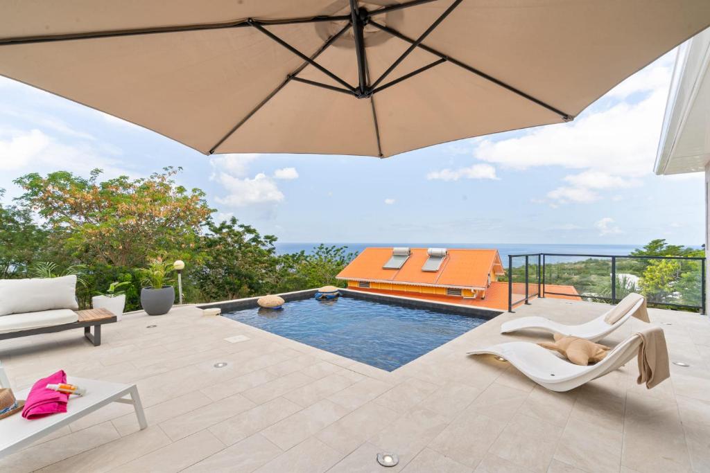 a patio with a pool and an umbrella at Villa Pomelia in Le Carbet
