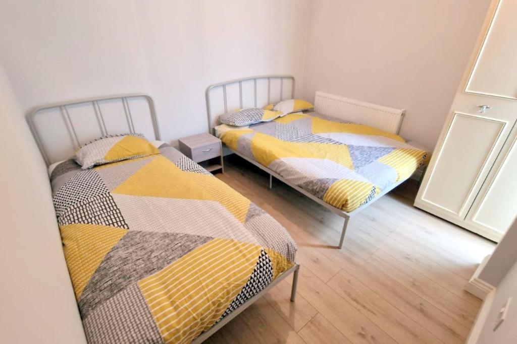two twin beds in a room with a mirror at 2-bedroom flat in Central Sutton in Sutton