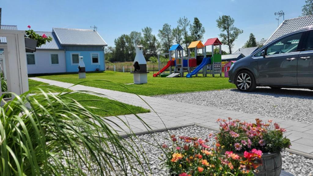 a car parked next to a park with a playground at Domki letniskowe Pastelowe Ustronie in Ustronie Morskie
