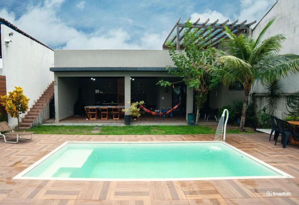 a swimming pool in front of a house at Casa pet friendly c piscina churrasqueira e wi-fi in Jaconé