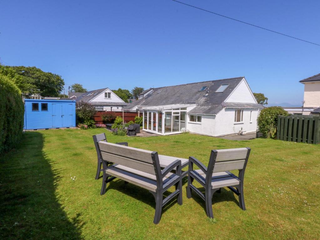 two benches sitting in the grass in front of a house at Swn Y Don in Llanbedrog