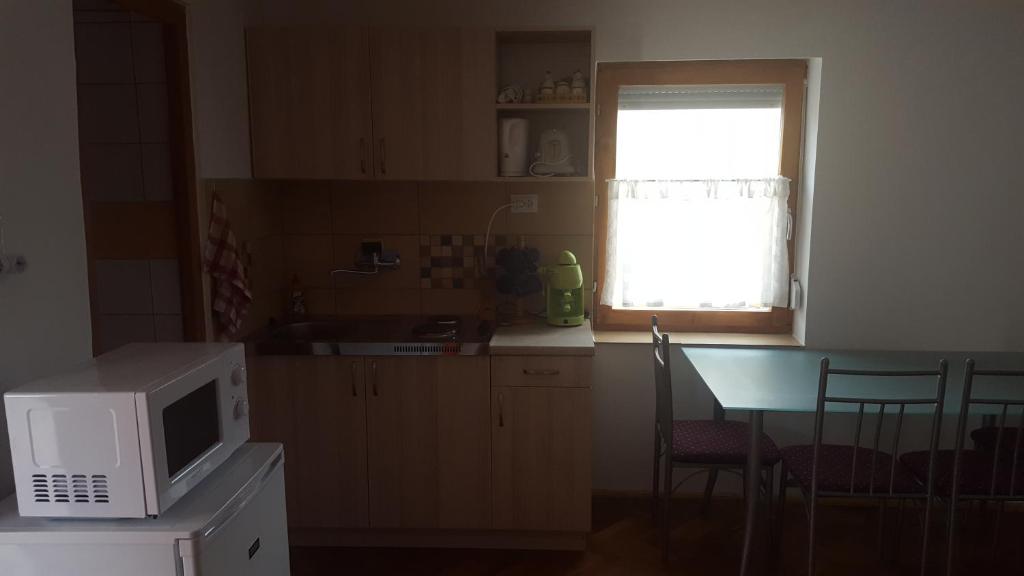 a kitchen with a table and a microwave and a window at M&M Apartman in Tiszafüred