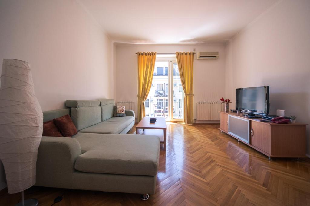 een woonkamer met een bank en een tv bij Apartment Kruna Center in Podgorica