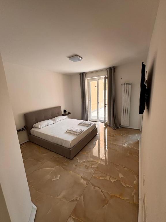 a white bedroom with a bed and a large window at Casa Florean in Cicciano