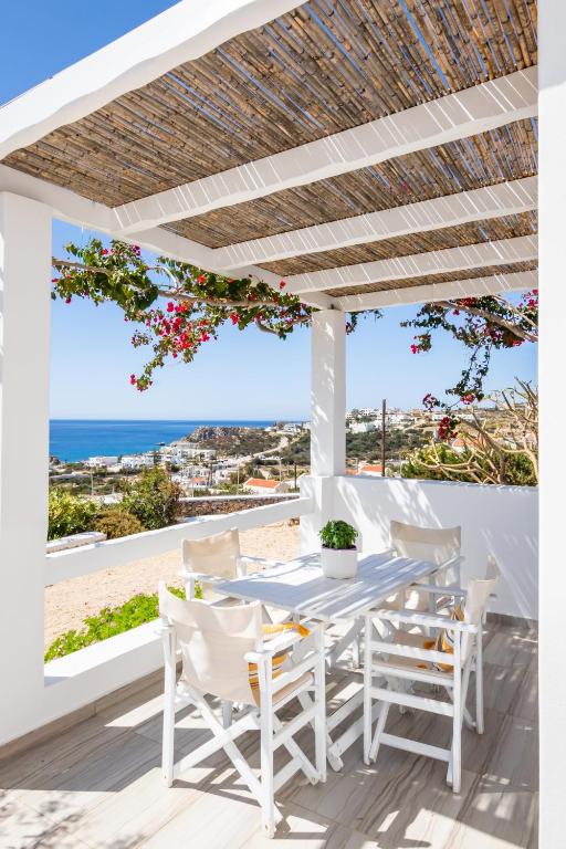 a white porch with a table and chairs and the ocean at Silene Villas in Amoopi