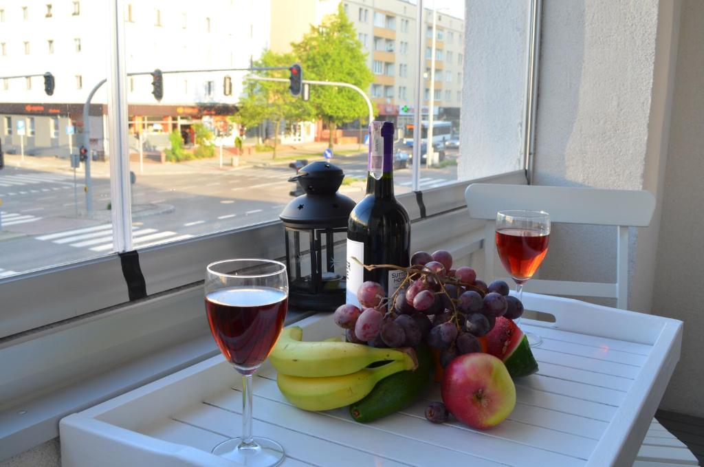 a table with two glasses of wine and a plate of fruit at BAiGO STAR in Gdynia