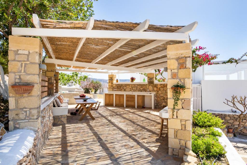 a patio with a wooden pergola and a table at Silene Villas in Amoopi