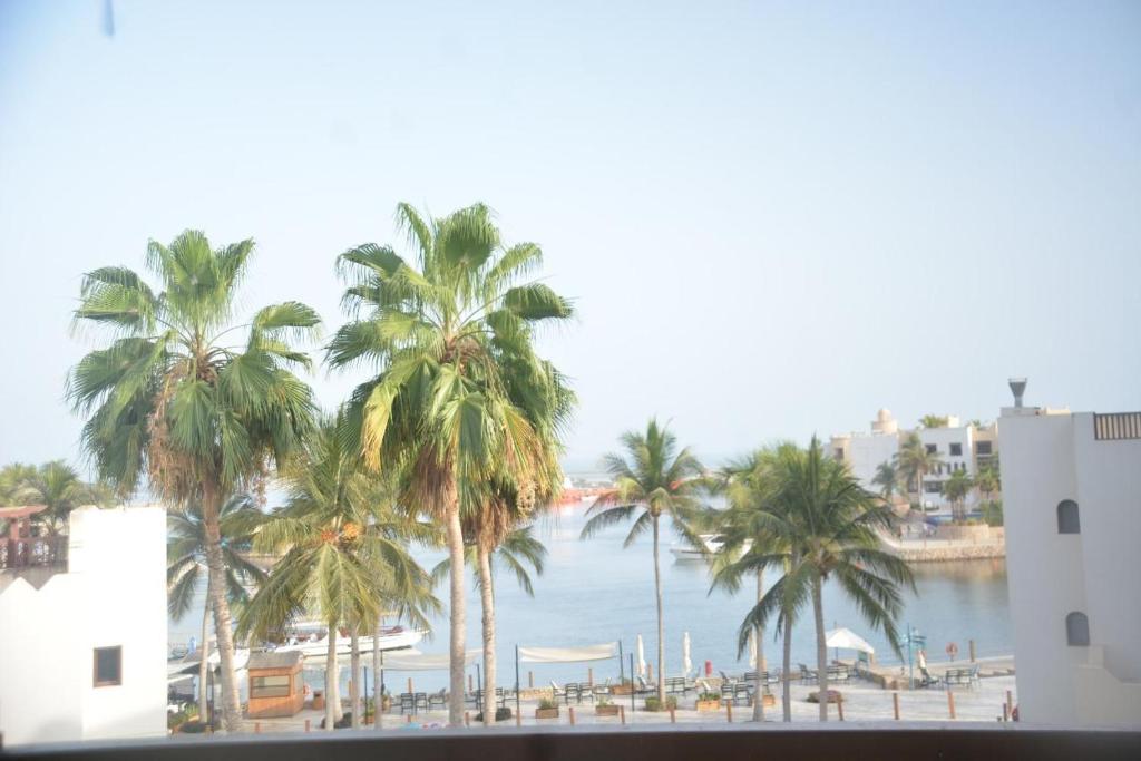 a view of a beach with palm trees and the water at Segal Hawana Salalah 2 Bedroom Marina in Salalah