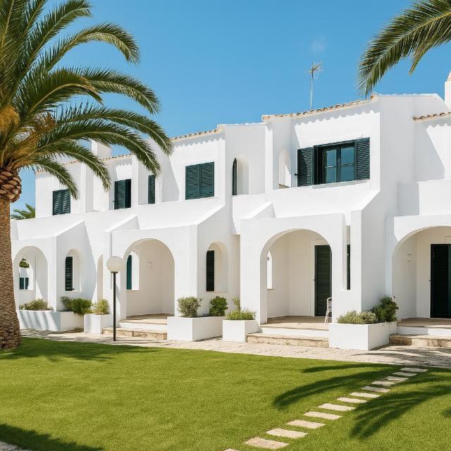 a large white building with palm trees in front of it at Costa Mernorca in Son Xoriguer