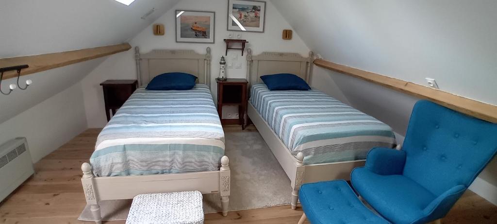 deux lits et une chaise bleue dans un grenier dans l'établissement La Goélette Beau duplex A 150 m du centre ville et 400m de la plage de l'écluse, à Dinard