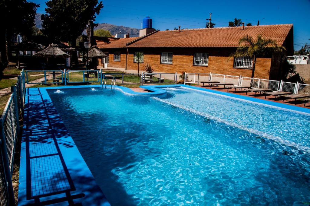 Una piscina con agua azul frente a un edificio. en Clima Sol, en Merlo