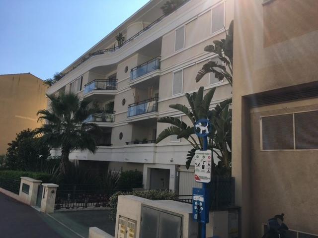 un grand bâtiment avec un palmier devant dans l'établissement Le Carre Montfleury Cannes, à Cannes