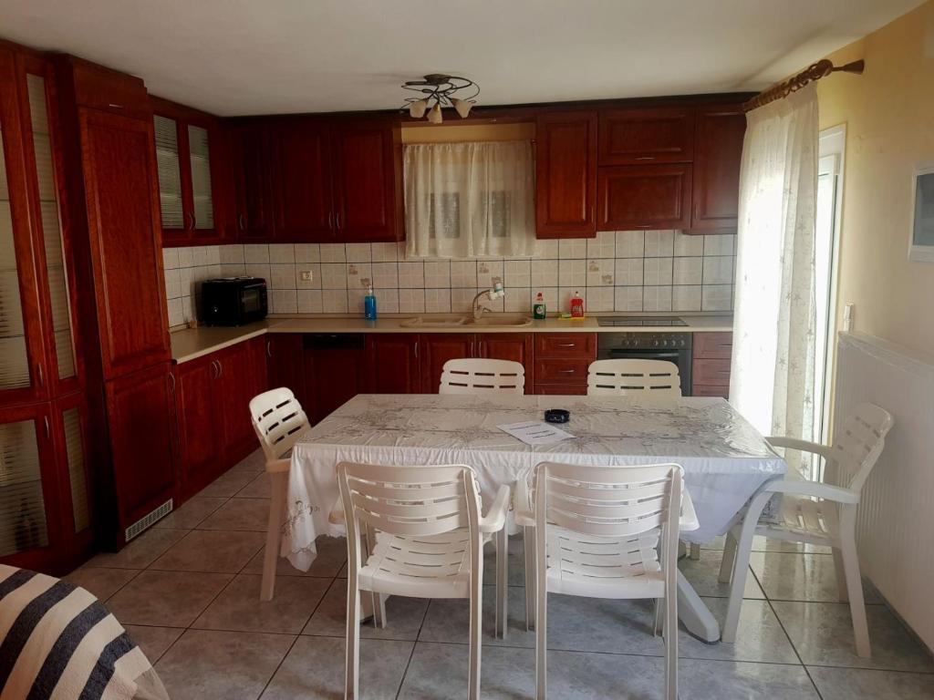 eine Küche mit einem weißen Tisch und weißen Stühlen in der Unterkunft νέα ηρακλειτσα όμορφο διαμέρισμα in Nea Iraklitsa