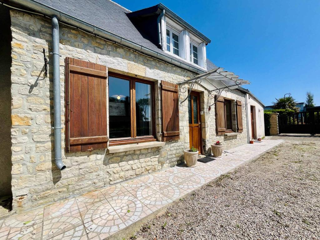 a stone house with wooden doors and windows at La Maison d Utah Beach and Memory in Sainte-Marie-du-Mont
