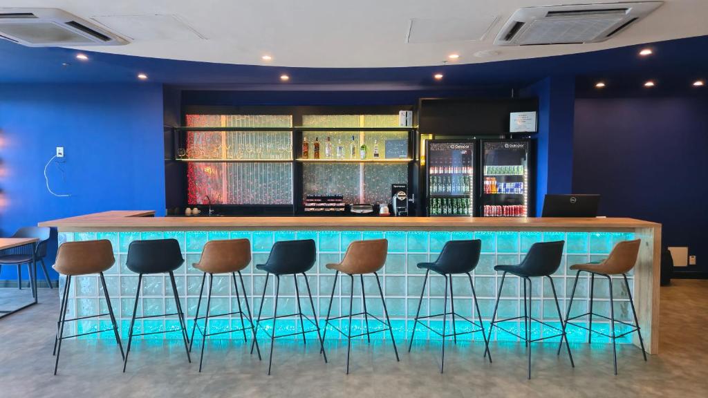 Un bar con una fila de taburetes en una habitación. en Ibis Styles Macaé, en Macaé