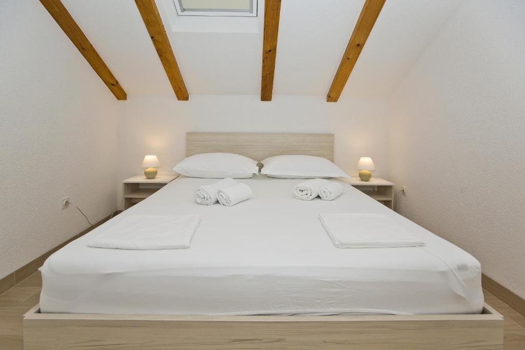 una camera da letto con un letto bianco con due comodini di Apartments and Rooms Zvjezdana a Hvar