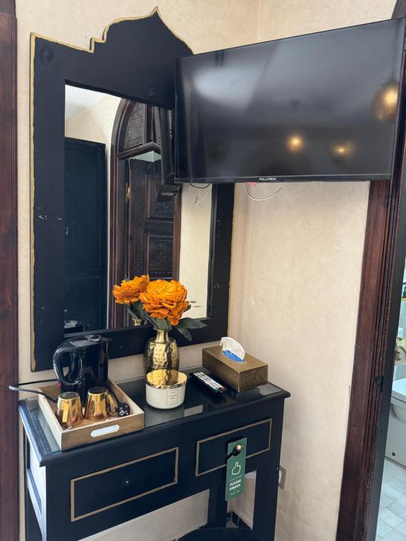 a table with a mirror and a vase with flowers on it at Riad M'Barka in Tangier