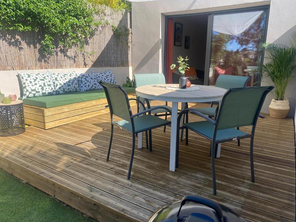a patio with a table and chairs on a deck at maison jardin tram,mer 15mn voiture in Saint-Jean-de-Védas