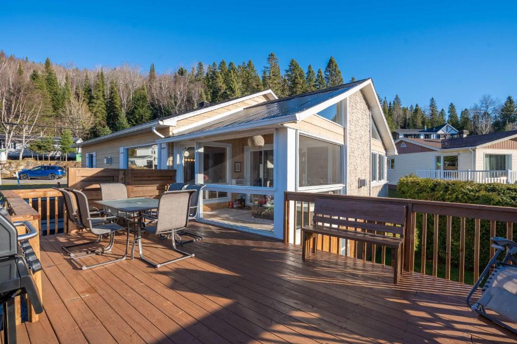a deck with a table and chairs on a house at La Zenitude Spa & Lake View in Saint Zenon