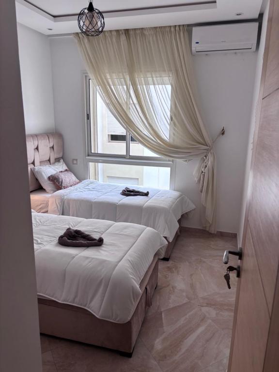 une chambre avec trois lits et une fenêtre dans l'établissement Shems Bouznika, à Bouznika