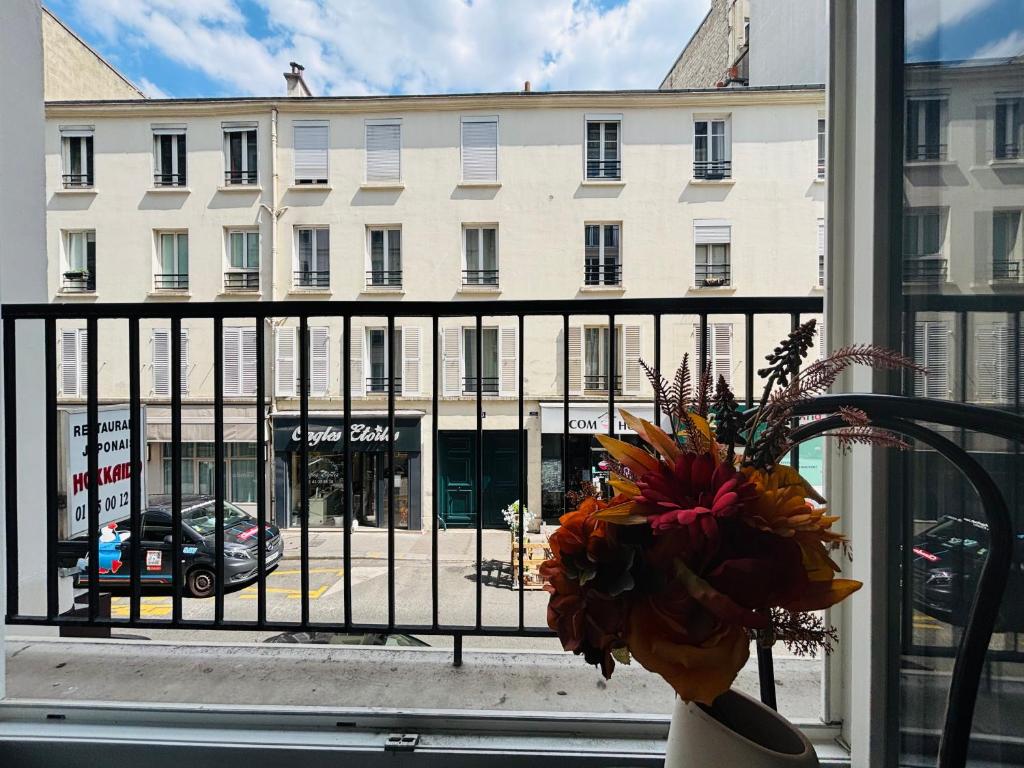 une vue d'un bâtiment depuis une fenêtre avec un vase de fleurs dans l'établissement Apart 300m to Arc de Triomphe, à Paris
