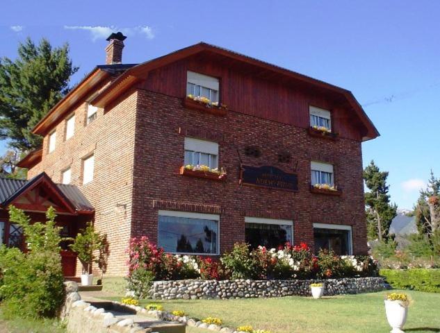 a large brick building with windows and flowers at Hosteria Nuevo Pinar in San Carlos de Bariloche