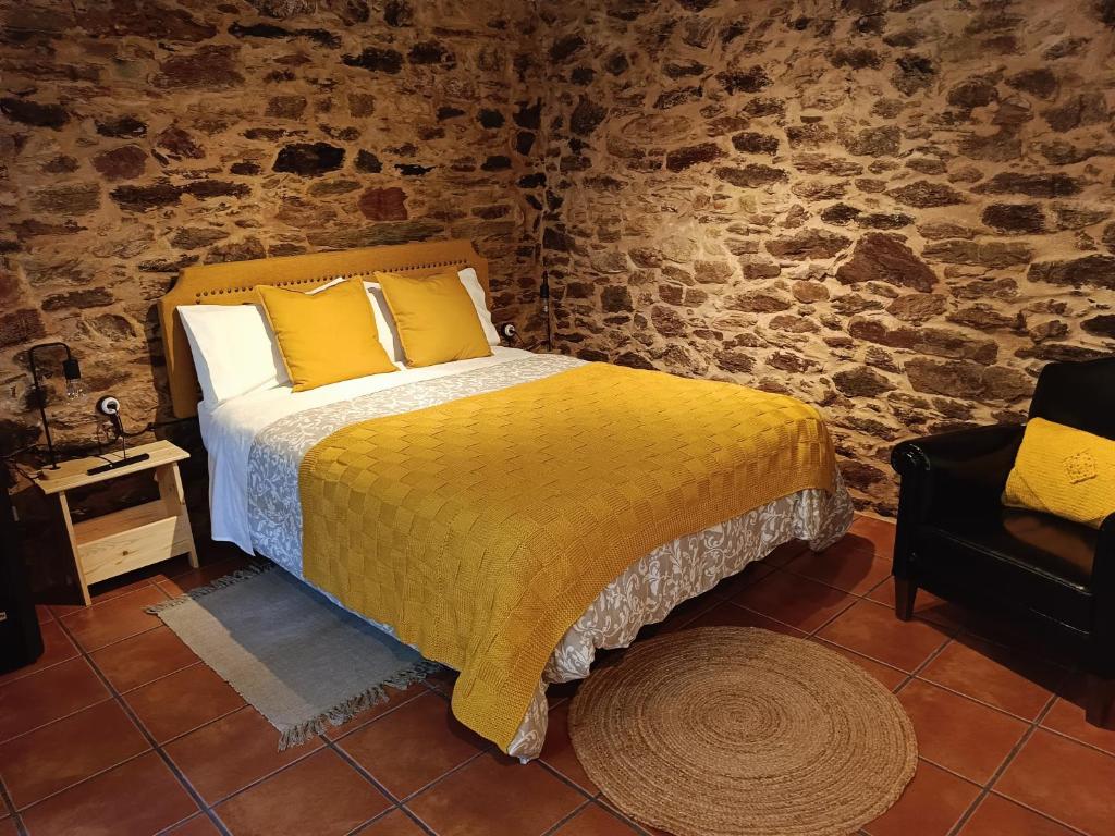 a bedroom with a bed with yellow sheets and a chair at Nuevo sabor rural Ribeira Sacra in A Pobra do Brollon