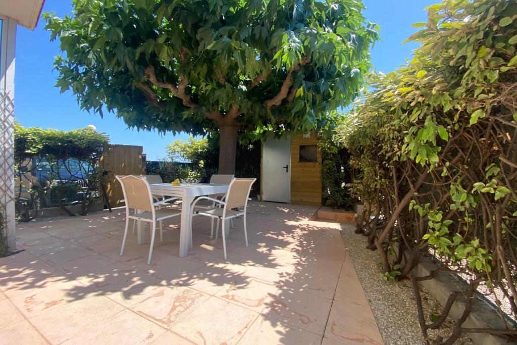 une table et des chaises sous un arbre sur une terrasse dans l'établissement a garden on the port, à Frontignan