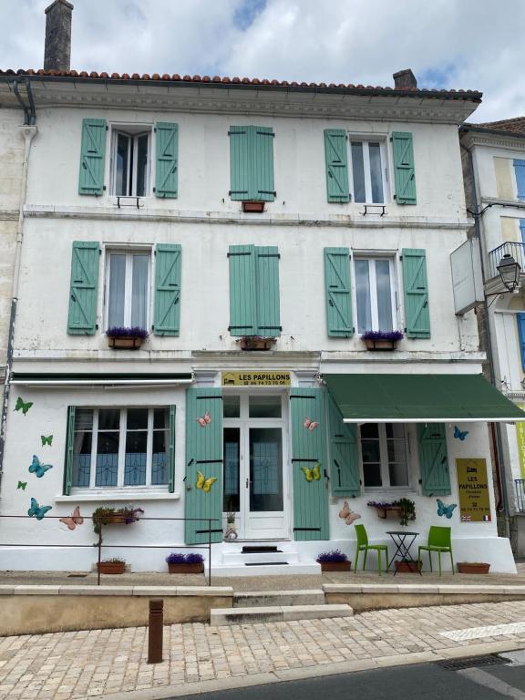 un bâtiment blanc avec volets verts dans une rue dans l'établissement Les Papillons, à Verteillac