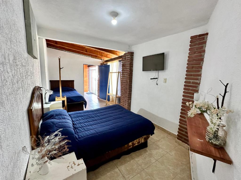 a bedroom with a blue bed and a television at La Palma, Suites Campestres in Jocotitlán