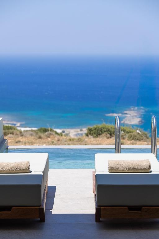 two beds sitting on a patio with a view of the ocean at Mouria Luxury Suites - Adults Only in Falasarna