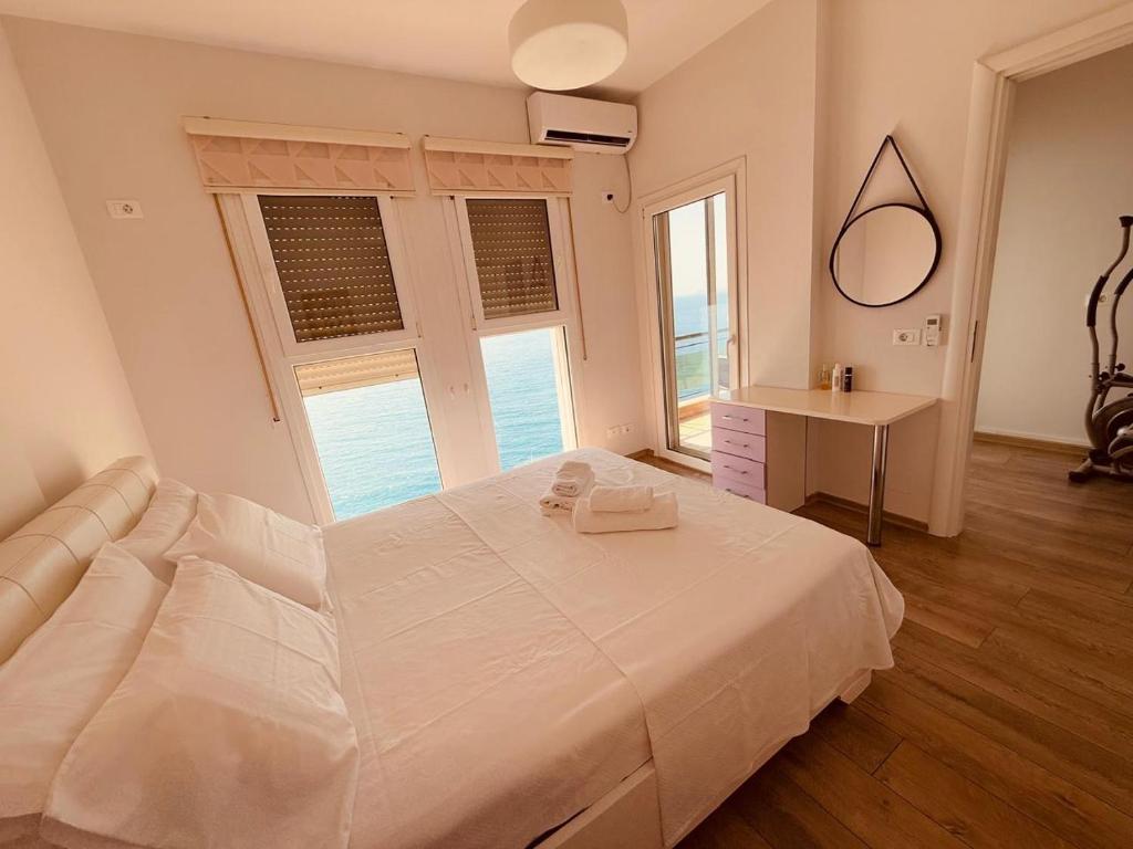 a bedroom with a large white bed and a desk at The Blue Horizon in Vlorë