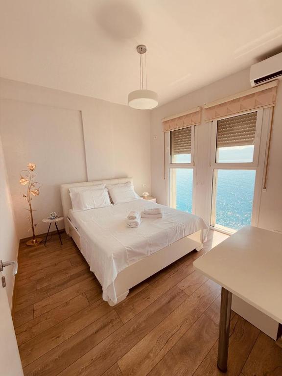 a white bedroom with a bed and a large window at The Blue Horizon in Vlorë